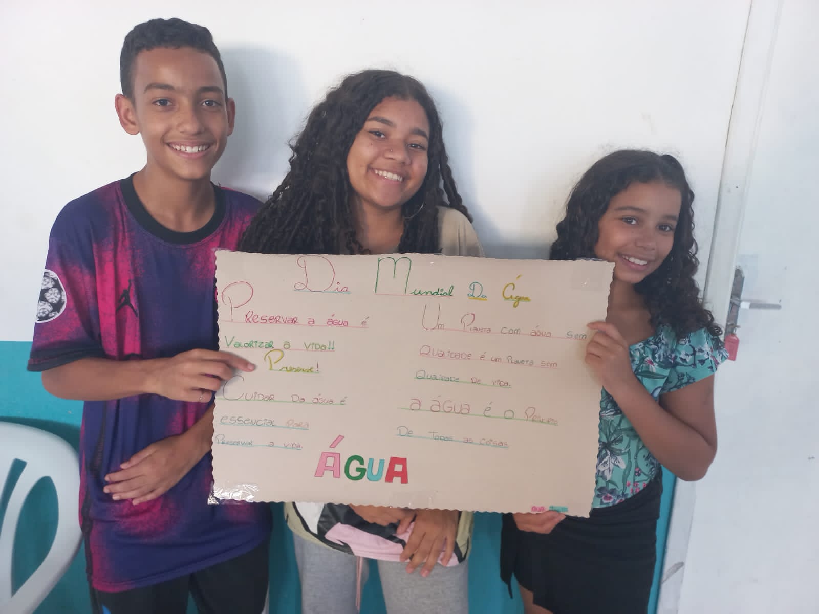 Duas meninas e um menino estão mostrando o cartaz que produziram sobre o Dia Mundial da Água