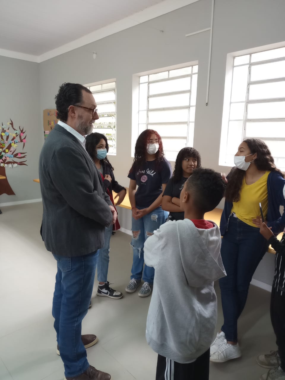 Secretário Carlos Bezerra Jr. em pé conversando com cinco crianças em uma roda.