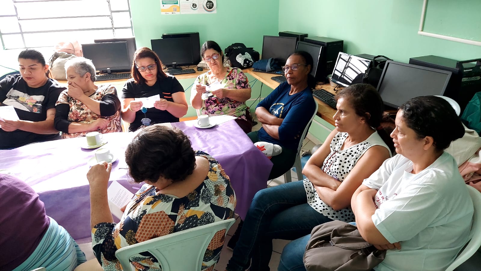 Mulheres estão em volta de uma mesa conversando após participarem de uma dinâmica.