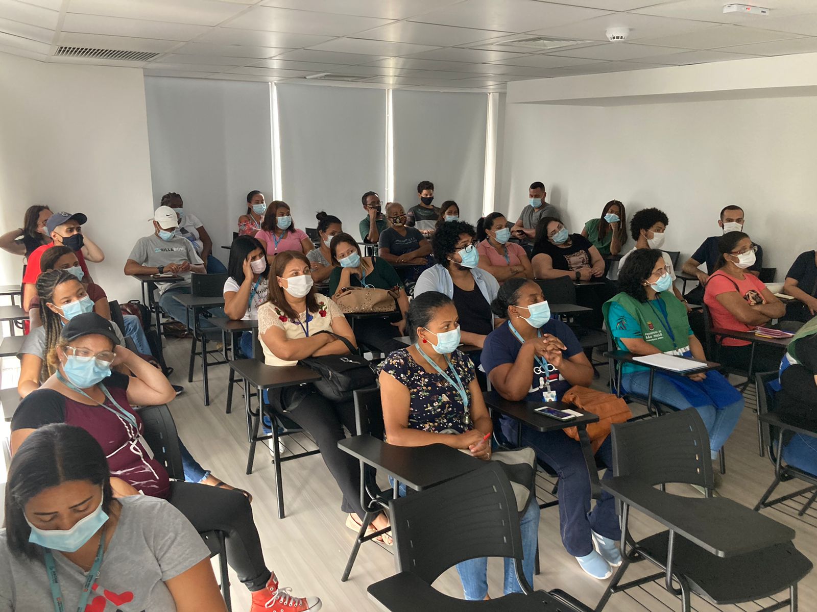 Orientadores reunidos e sentados em cadeiras assistindo ao treinamento no auditório 