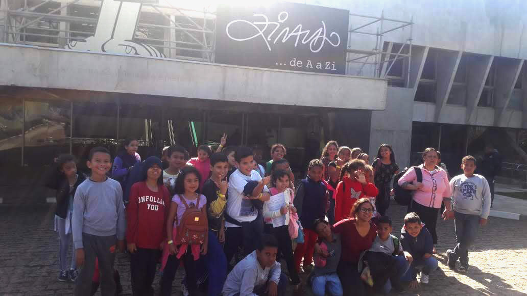 Cerca de vinte e nove crianças e duas mulheres em frente à entrada da exposição Ziraldo.. de A a Zi em pose para foto