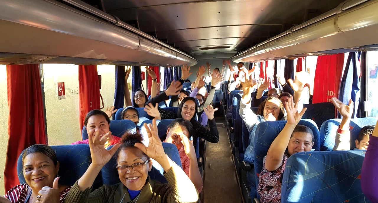 Conviventes sentados dentro do ônibus de passeio com as mãos para cima em pose alegre para foto