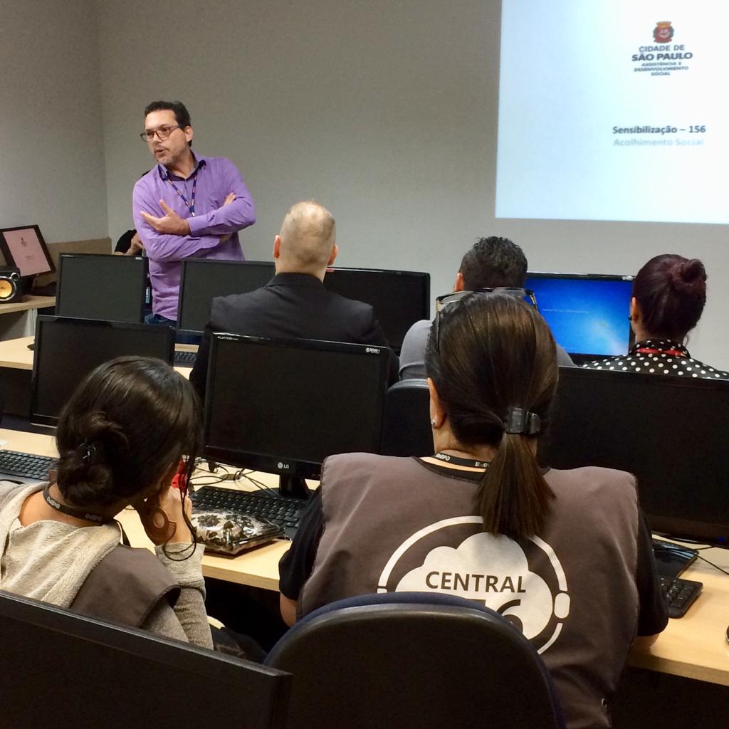 Coordenador de Pronto Atendimento Social, Edison Tomazi, fala em pé para operadores da Central São Paulo Um Cinco Meia, que estão sentados de frente para computadores. 