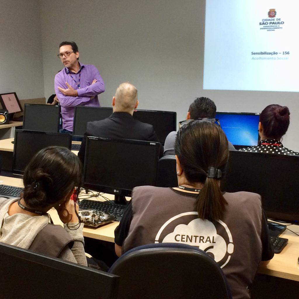 Coordenador de Pronto Atendimento Social, Edison Tomazi, fala em pé para operadores da Central São Paulo Um Cinco Meia, que estão sentados de frente para computadores. 