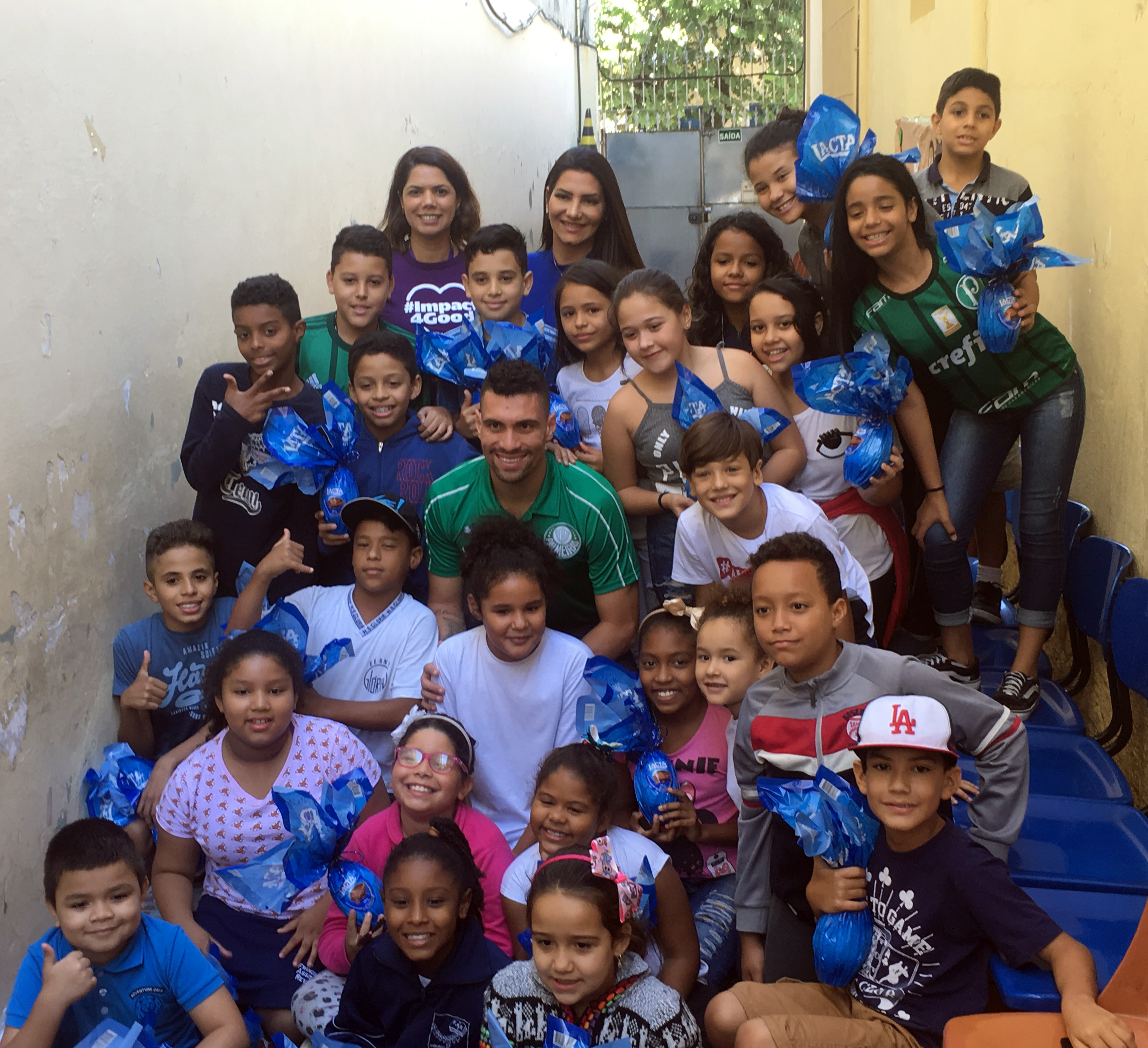 No corredor do CCA, crianças e adolescentes posam com os ovos junto com o jogador do Palmeiras Moisés. Na foto também estão a esposa e a representante da Mondelez.