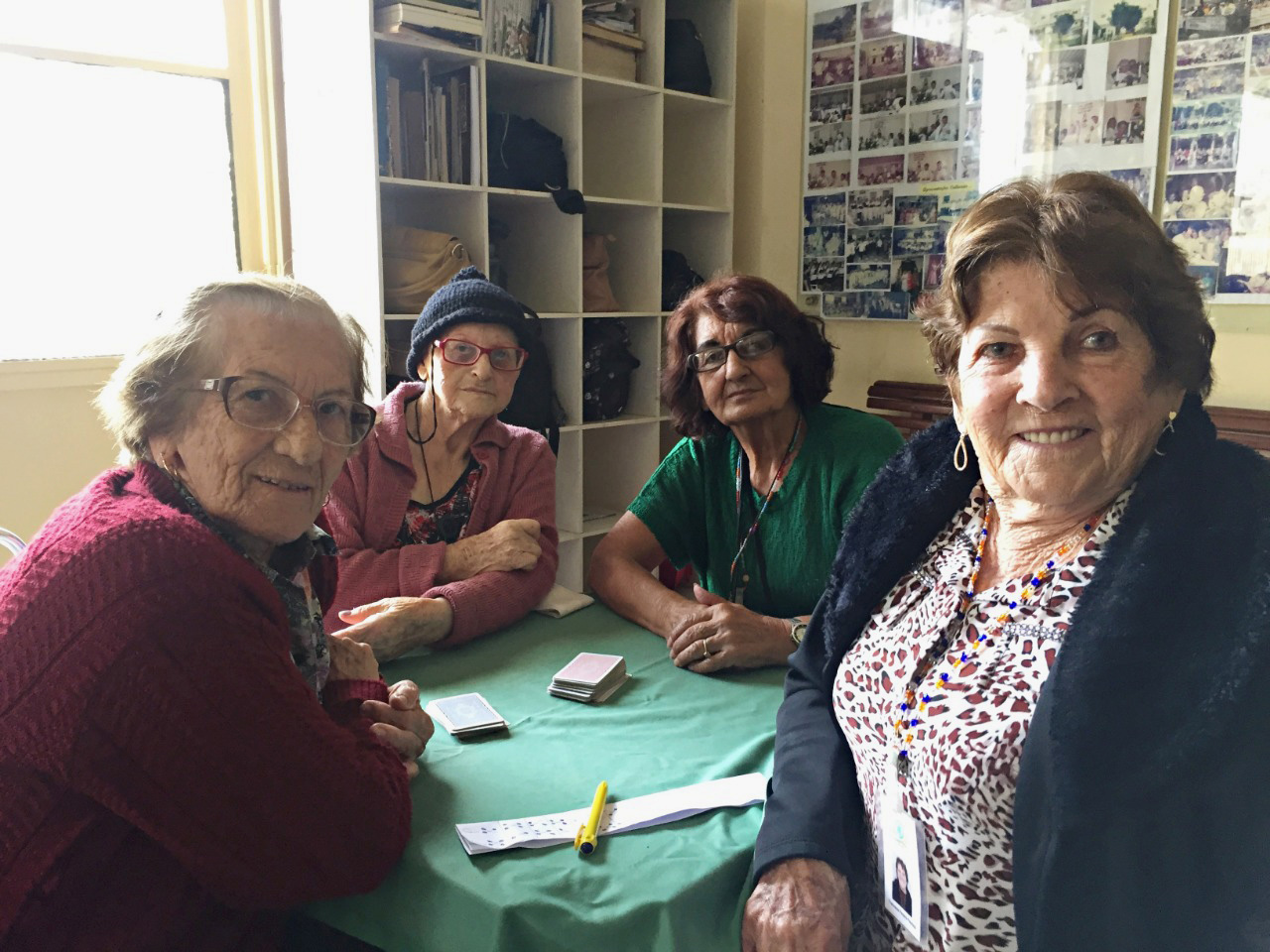 Quatro idosas posam para a foto durante jogo de cartas