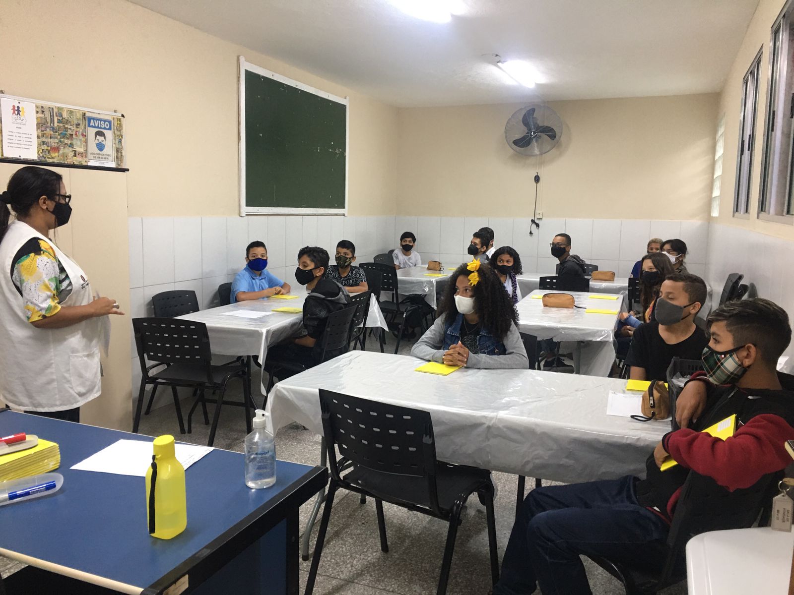Crianças se reunem para a roda de conversa em uma sala de aula, sempre acompanhados de um orientador.