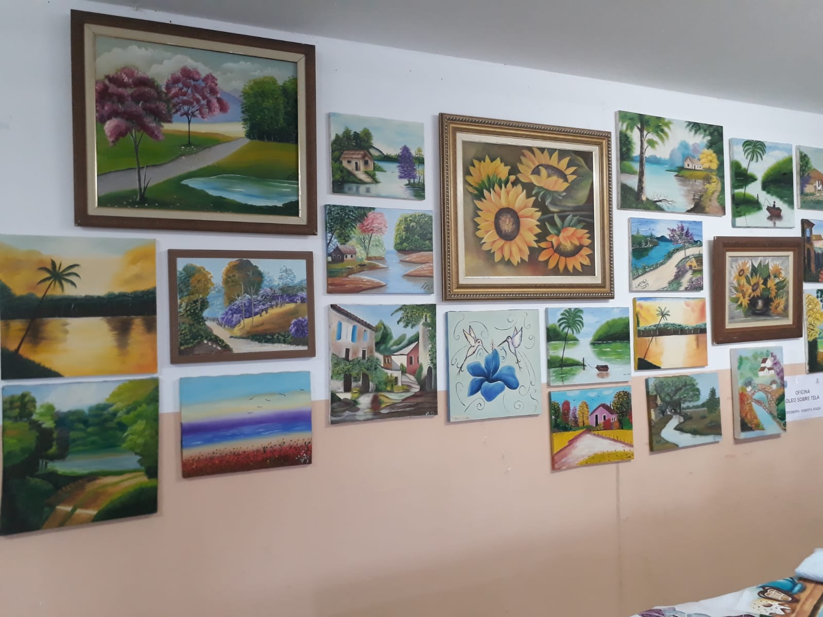 A imagem mostra uma parede com dezenas de telas pintadas, em quadros.