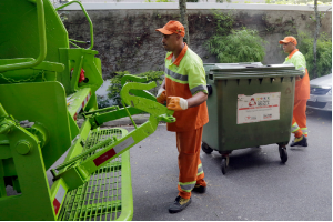 Coletores preparam caçamba de lixo para recolhimento no caminhão