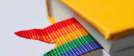 Livro com capa amarela e marcador de texto com as cores do arco-íris, símbolo LGBTI+.