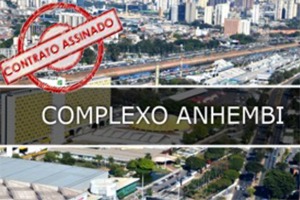 Fotografia tirada do alto, que mostra o sambódromo de São Paulo, Complexo Anhembi, no fundo tem a vários prédios e a marginal tietê, no meio escrito Complexo Anhembi