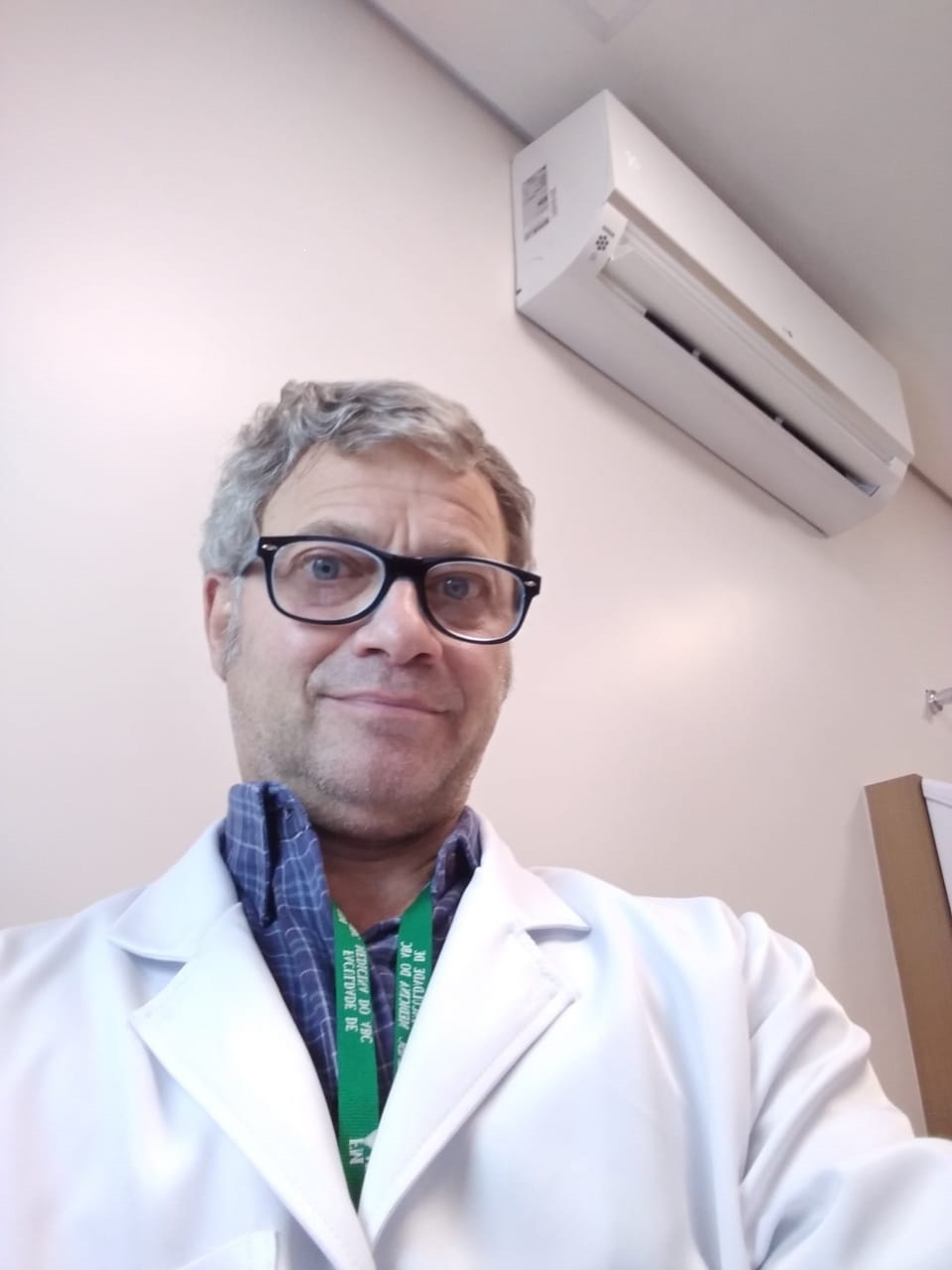 Selfie do médico, que está usando óculos e está usando jaleco branco