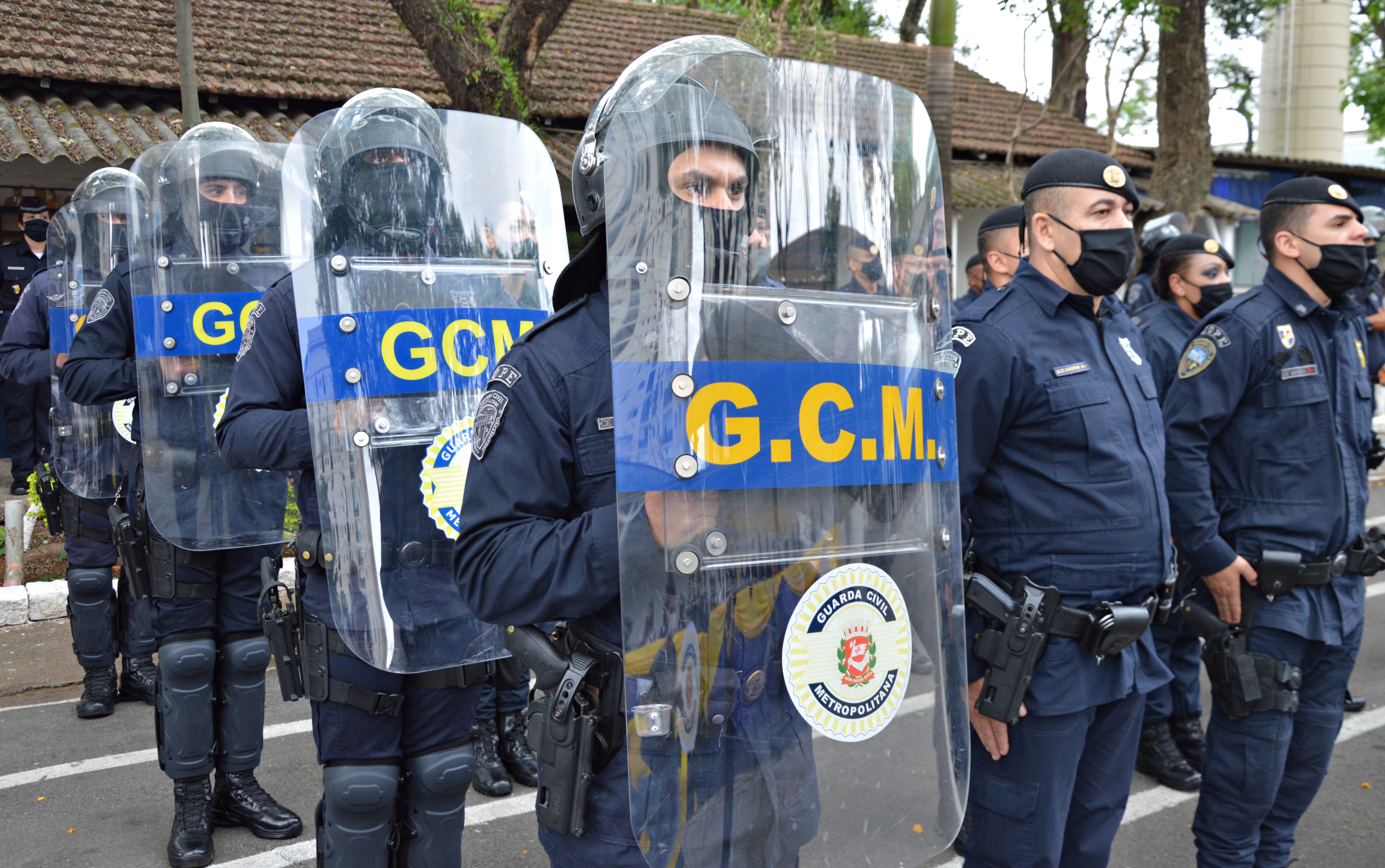 #pratodosverem Imagem de Guardas Civis Metropolitanos em formação, portando escudos com a descrição da GCM em amarelo.