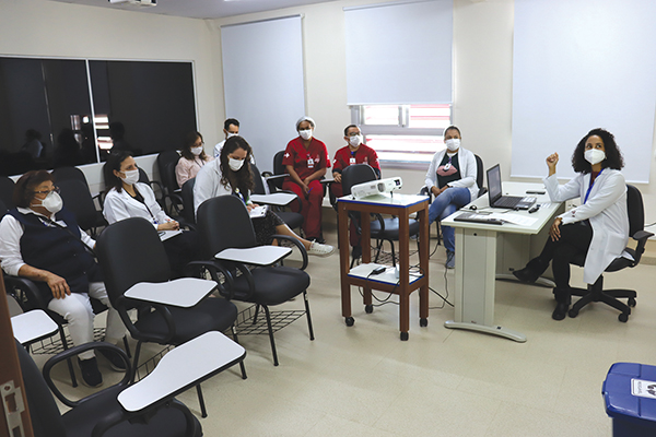 Imagem de sala de aula com participantes sentados e palestrante fazendo uma apresentação