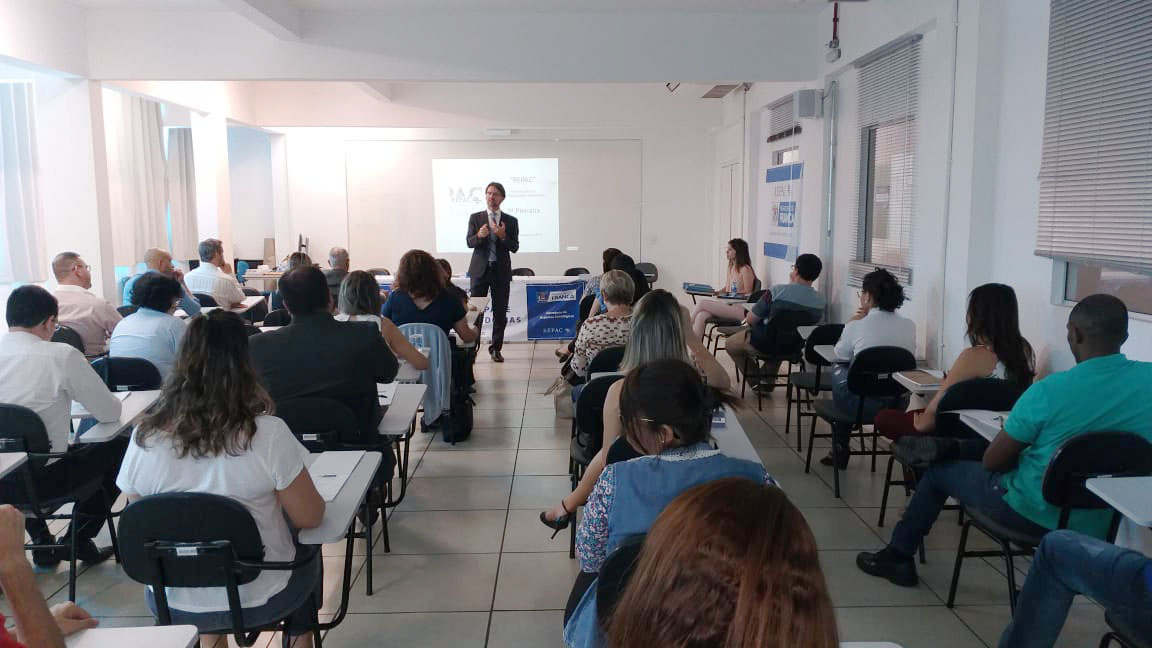 em uma sala, várias pessoas assistem a apresentação do Controlador Geral do Município de São Paulo, Gustavo Ungaro