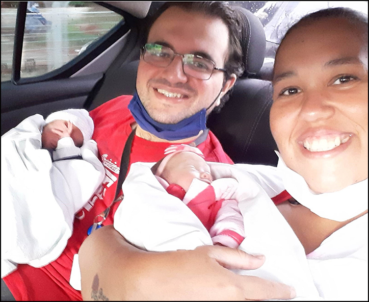 Foto de um casal e seus dois filhos bebês no carro