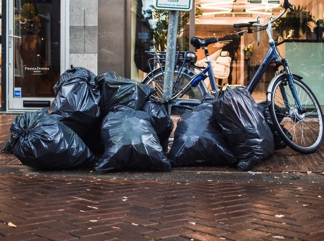 A imagem mostra aparentemente 10 sacos de lixo em frente a um comércio