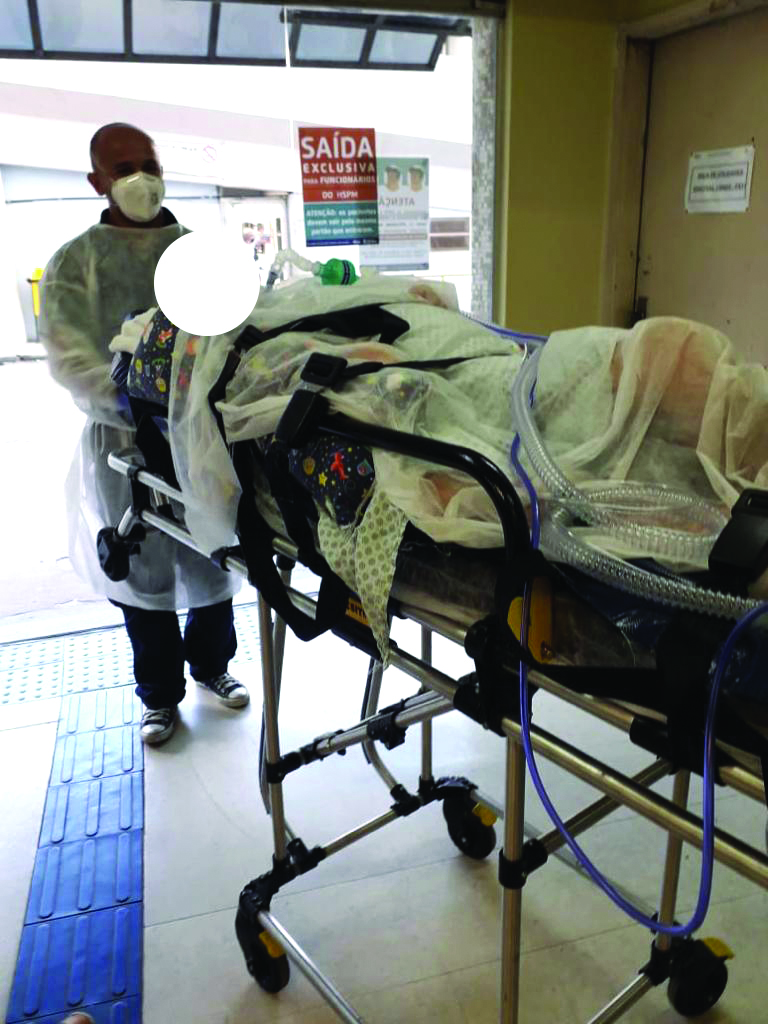 Enfermeiro levando paciente em maca para a saída do hospital