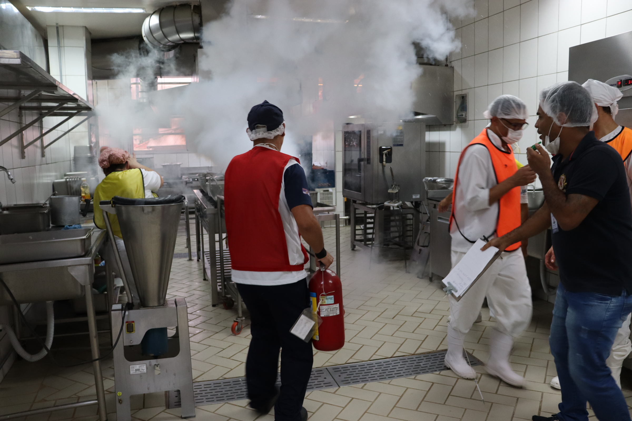 Imagem da Cozinha do HSPM e membro da equipe apagando o fogo com um extintor