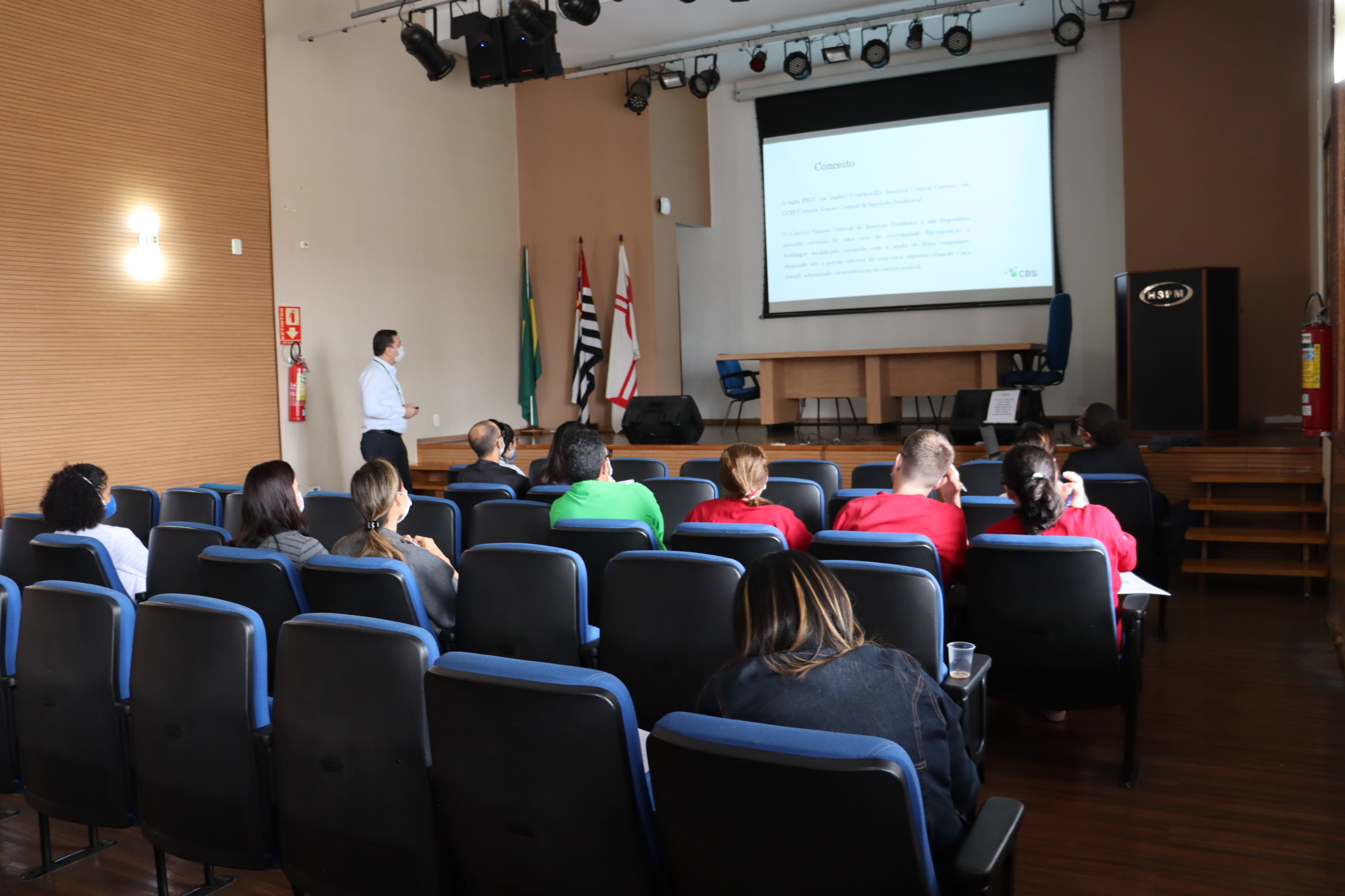 Imagem panorâmica do anfiteatro, mostrando participantes e palestrante realizando uma apresentação.