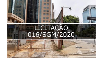 fotografia que mostra terreno de esquina, no fundo prédio comercial e no meio faixa transparente escrito Licitação 016/SGM/2020 .