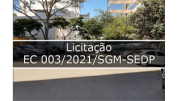 fotografia que mostra rua com carros estacionado, tem árvores e prédios no fundo. No meio tem faixa escrito Licitação  Ec 003/2021/SGM-SEDP