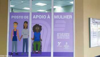 Imagem com o desenho de três mulheres, duas em pé e uma em uma cadeira de rodas. Fundo lilás e a frase Posto de apoio à mulher.