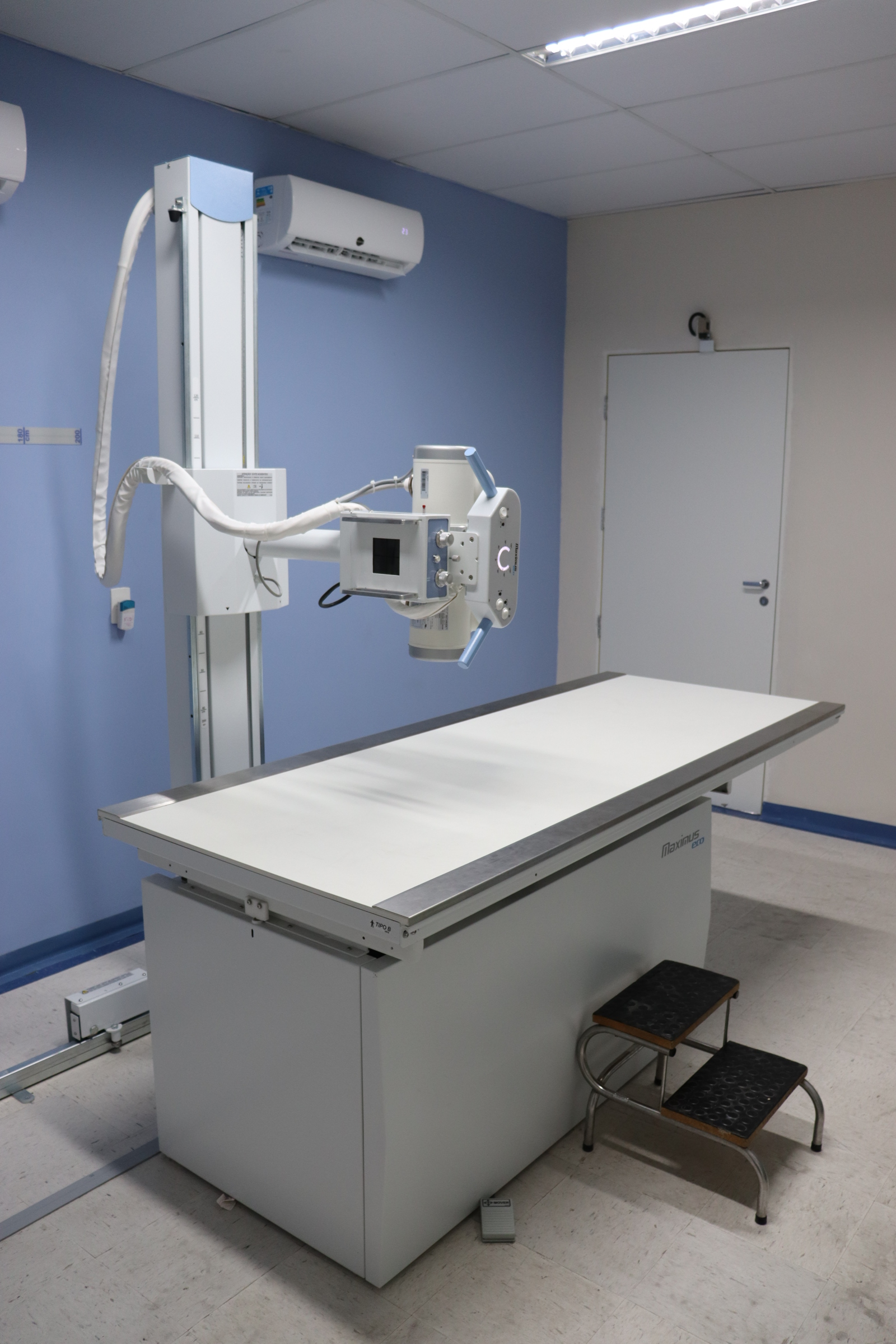 Imagem de um equipamento de Raio-X dentro  de uma sala de atendimento médico