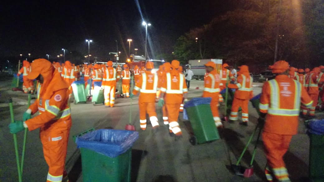 Varredores uniformizados coletando os resíduos na rua após evento.