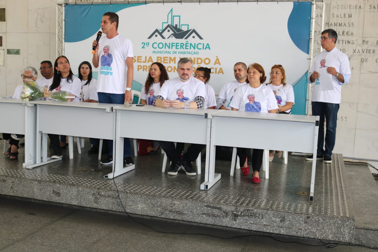 Representantes da 2ª Conferência em mesa observam discurso do Secretário João Farias