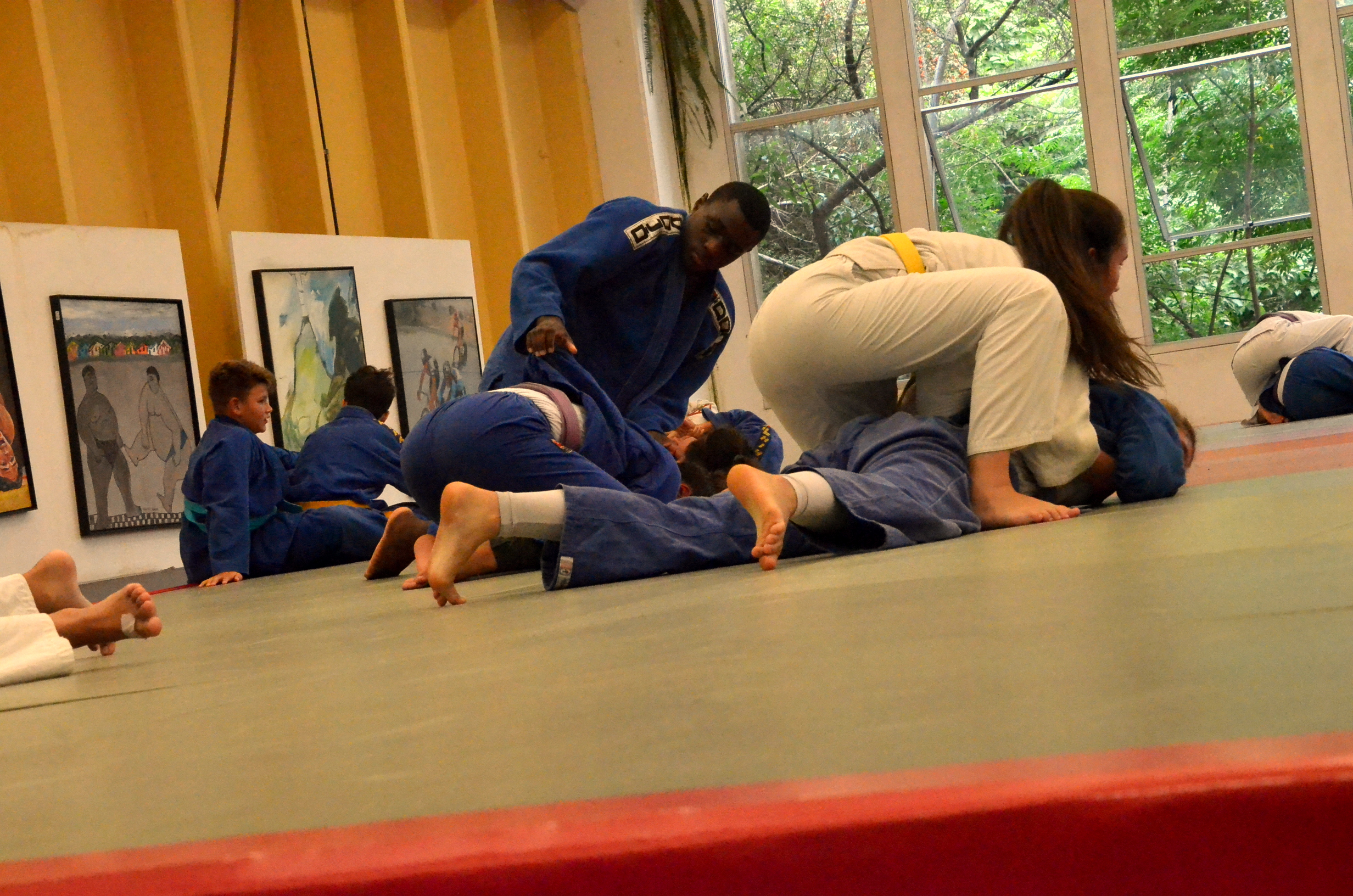 Dois atletas, um vestido com kimono azul outro com kimono branco, lutando no chão do tatame.