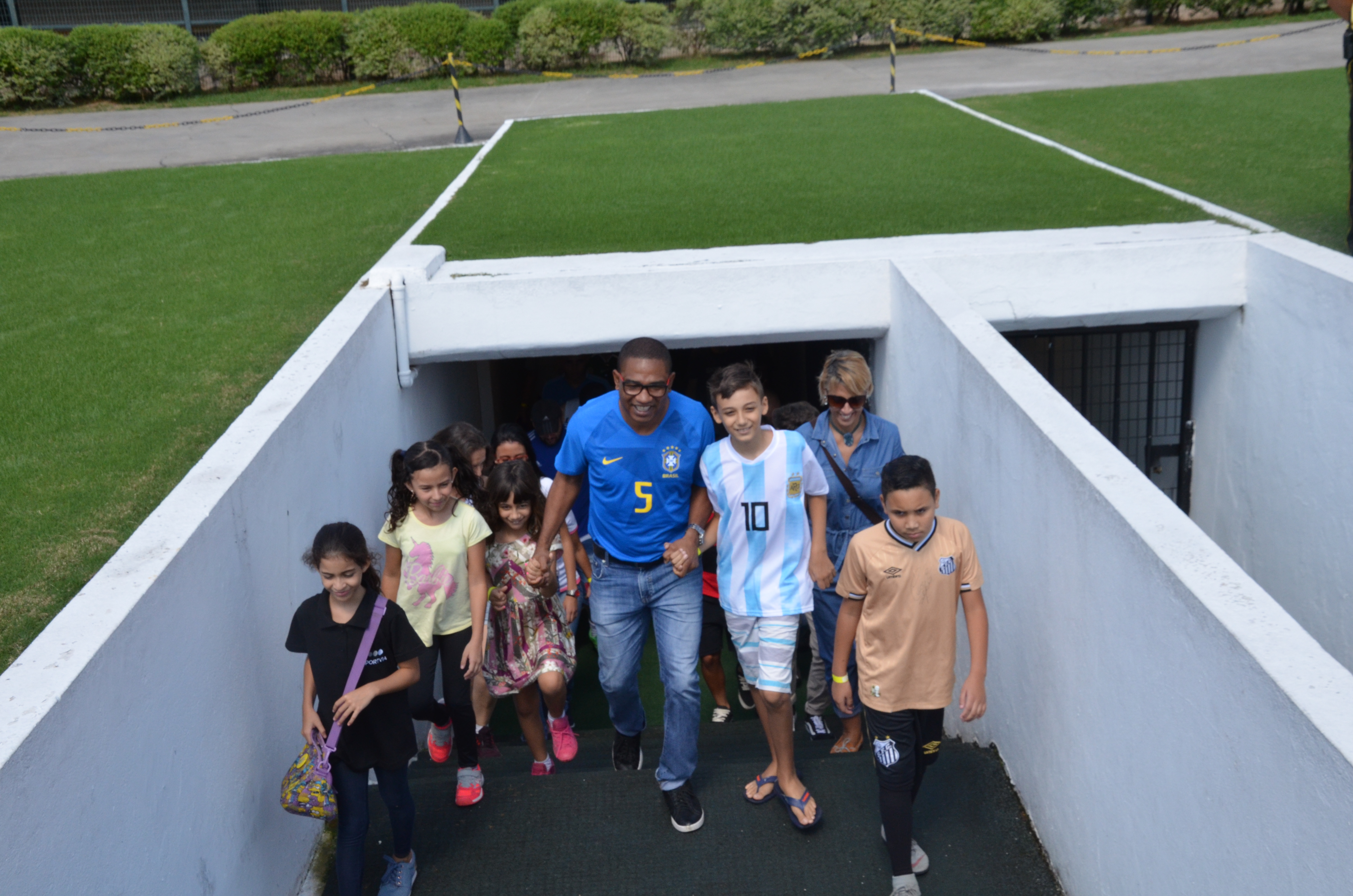 César Sampaio sobe as escadas que dão acesso ao gramado do Pacaembu de mãos dadas com crianças e demais participantes do Pacaemtour.