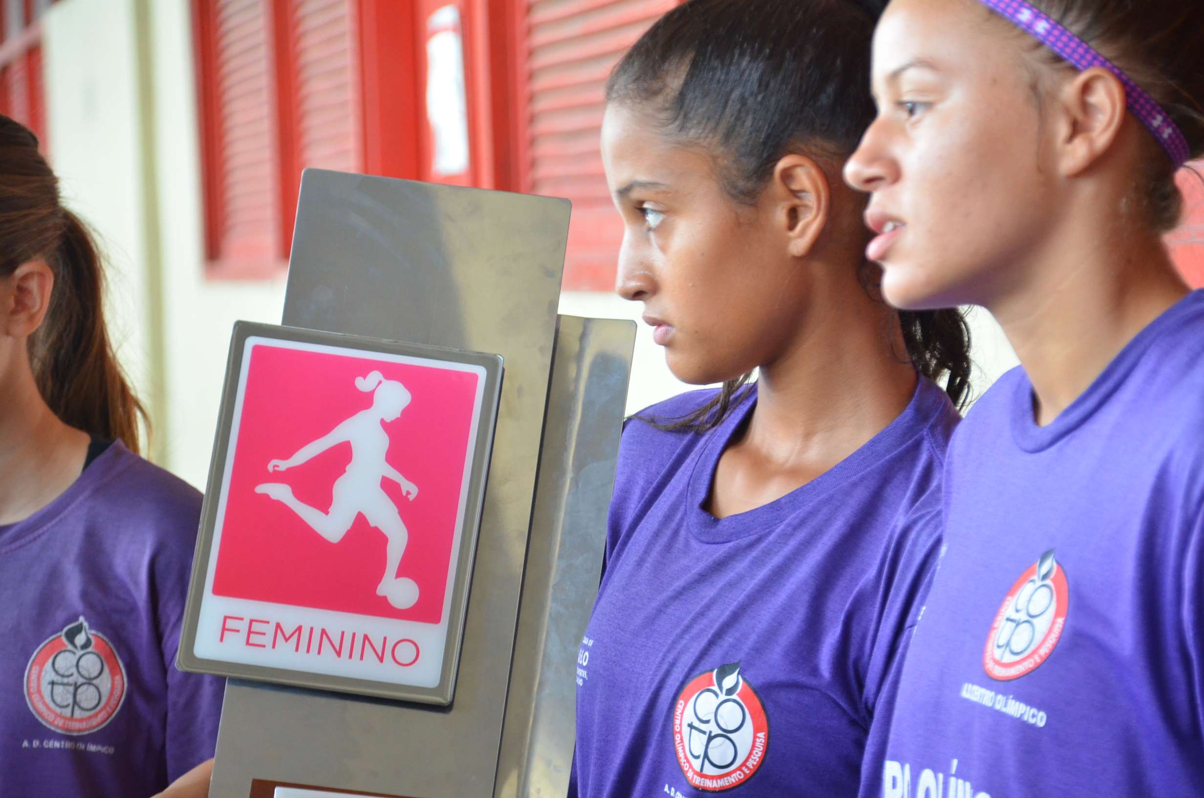 Meninas do futebol com uma placa em foco escrito 