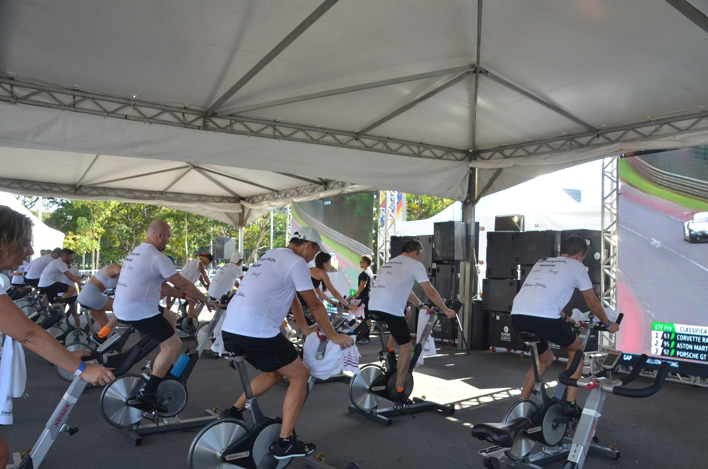 Competidores pedalando em uma bicicleta de spinning. 