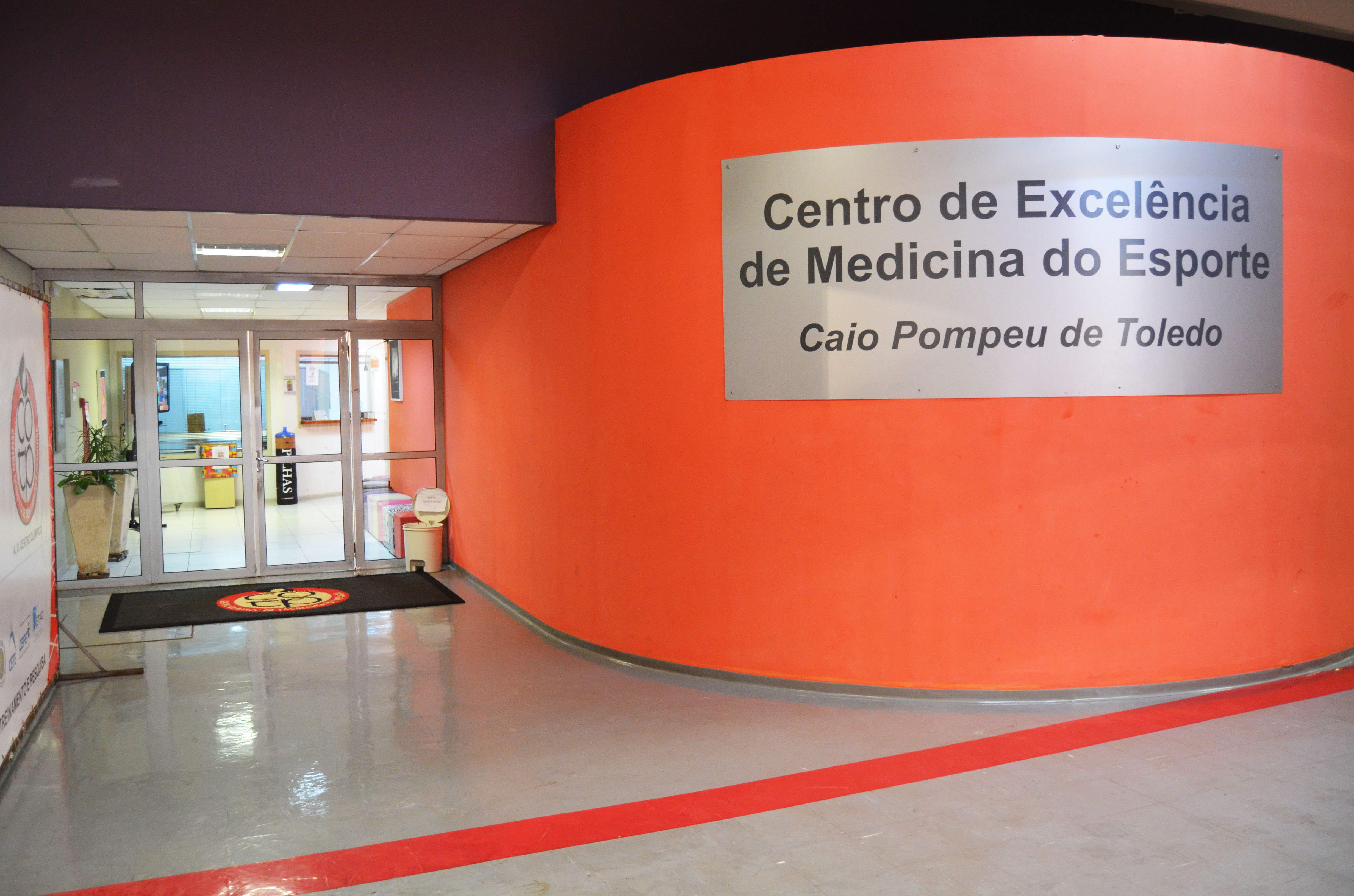 Entrada do Centro Médico do Centro Olímpico. À direita, uma placa metálica prateada mostra o nome do espaço e a homenagem a Caio Pompeu de Toledo.