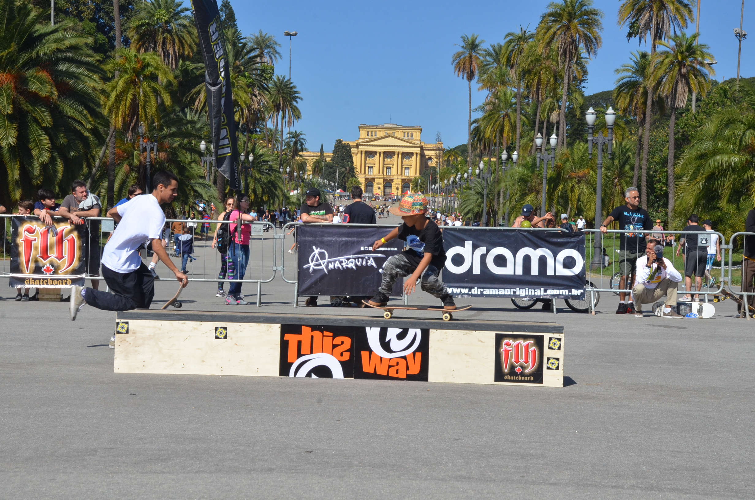 Jovens andando de skate com o Museu do Ipiranga ao fundo