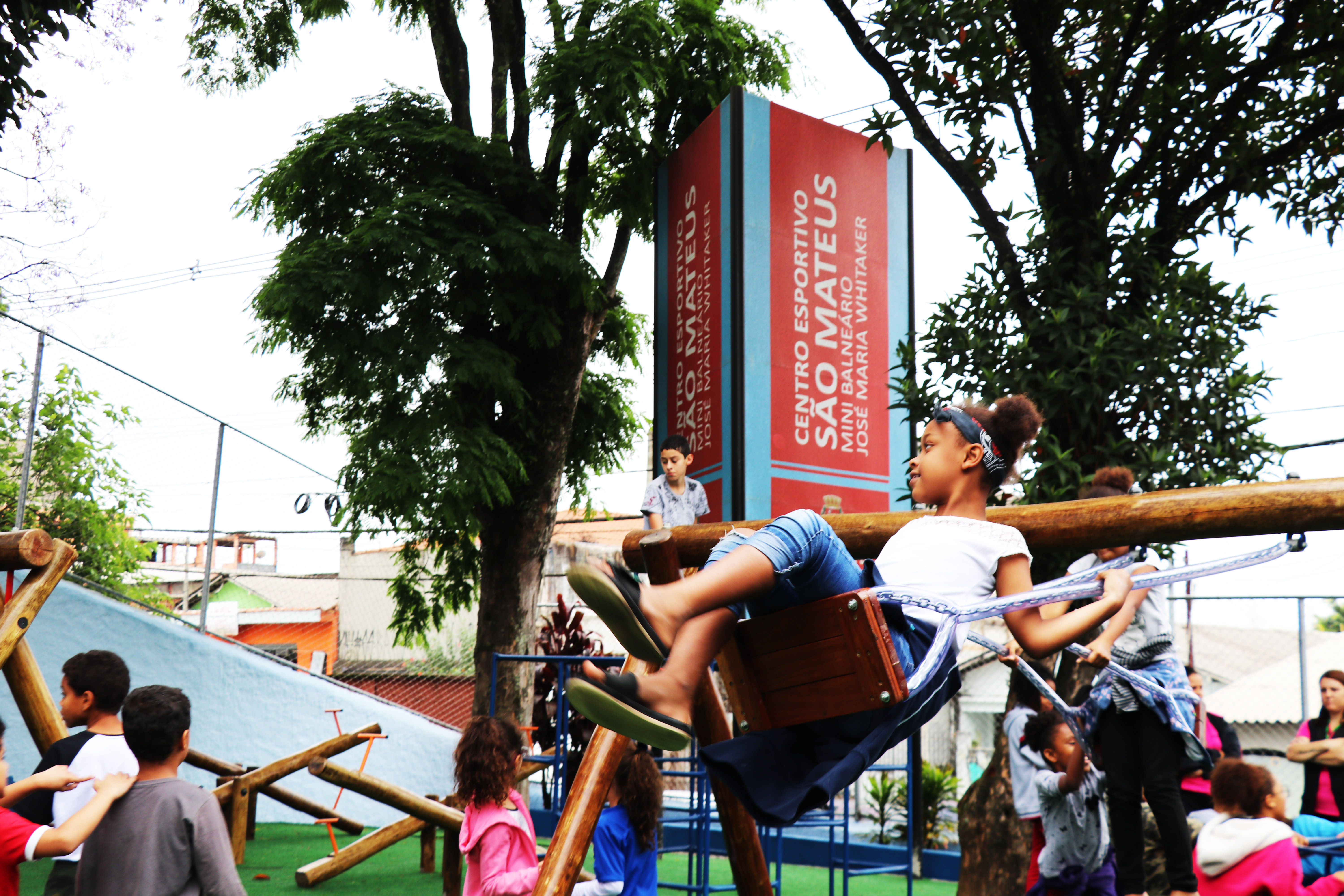 Na imagem, criança brinca em balanço. Ao fundo, placa do Centro Esportivo São Mateus.
