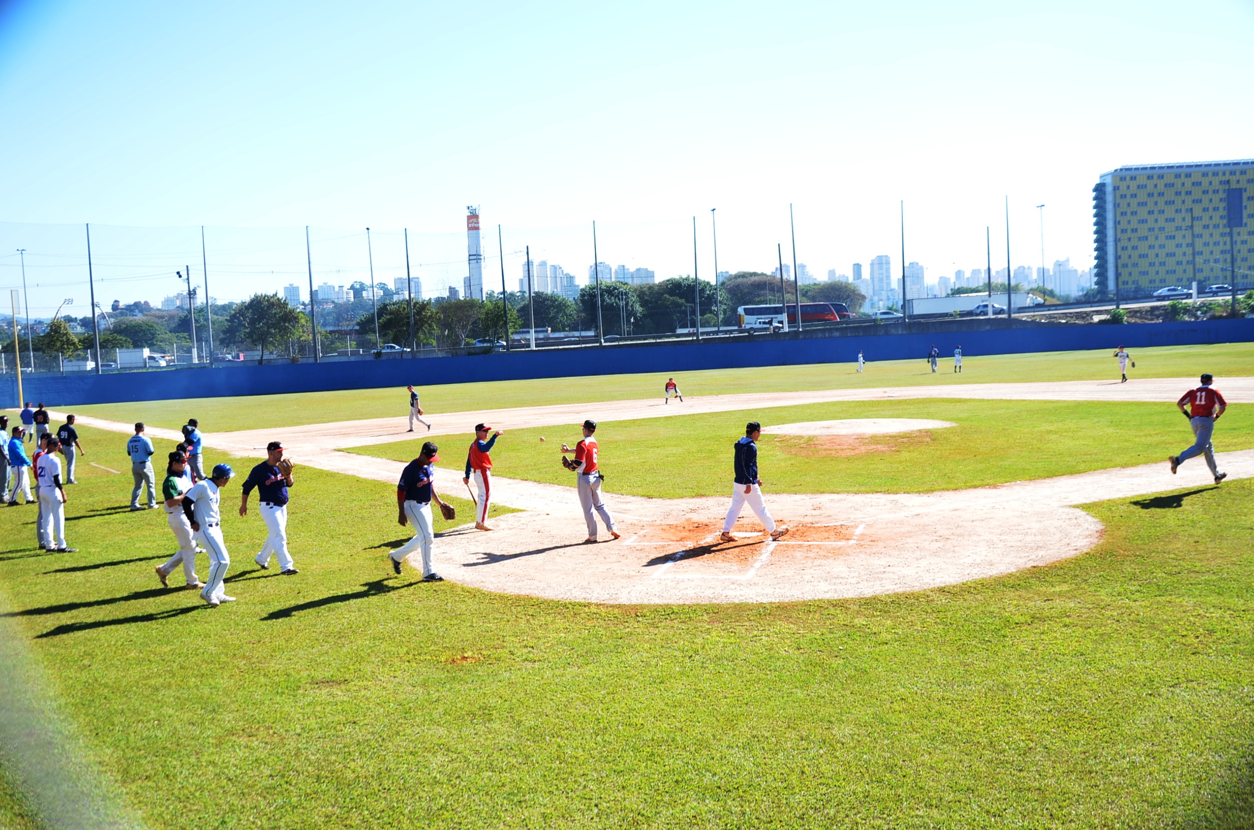 Na imagem jogadroes eu um campo de beisebol no Estádio Municipal de Beisebol Mie Nishi em um dia ensolarado.