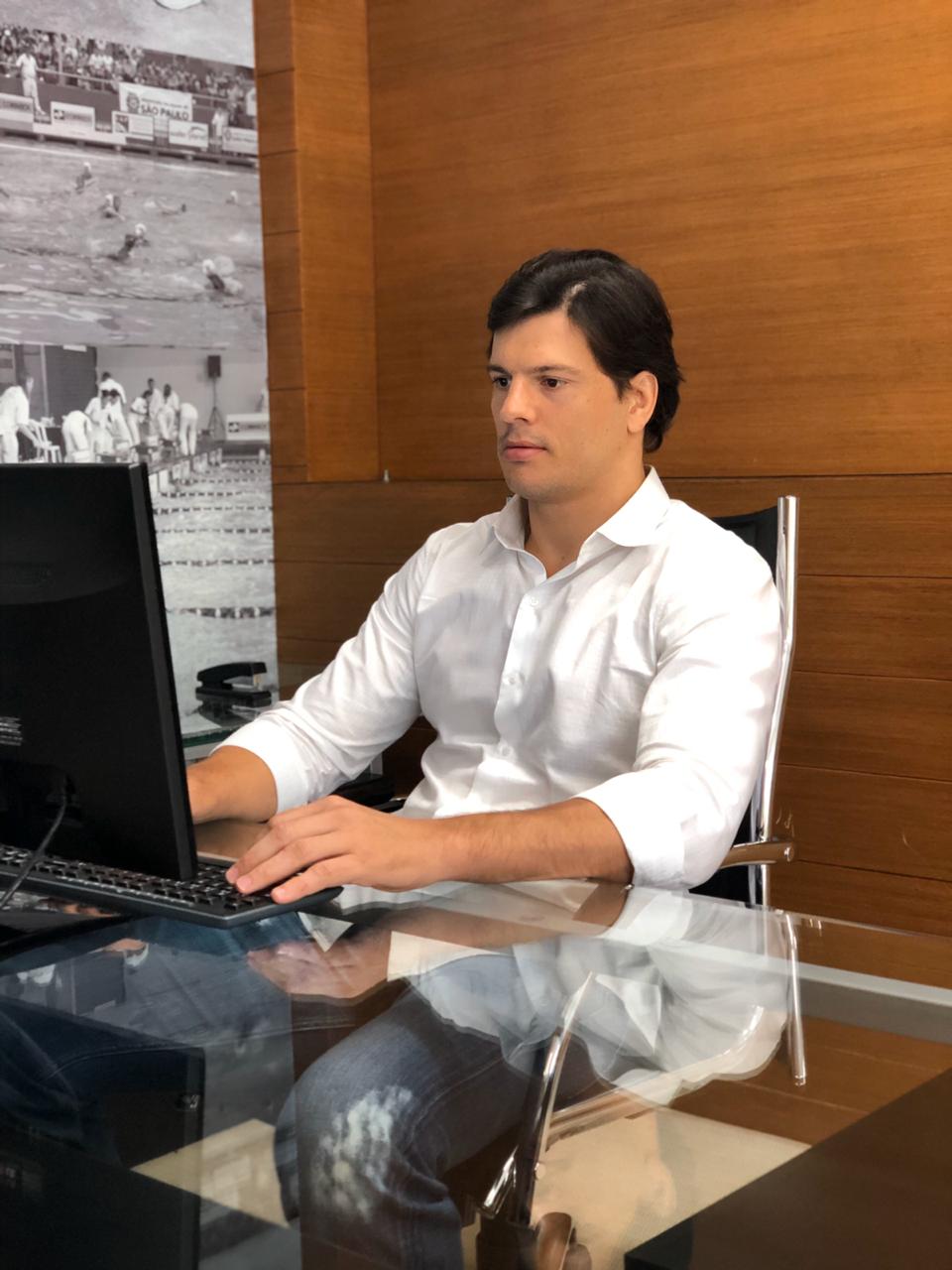 Secretário Municipal de Esportes e Lazer, Maurício Landim, sentando em sua mesa mexendo no computador.