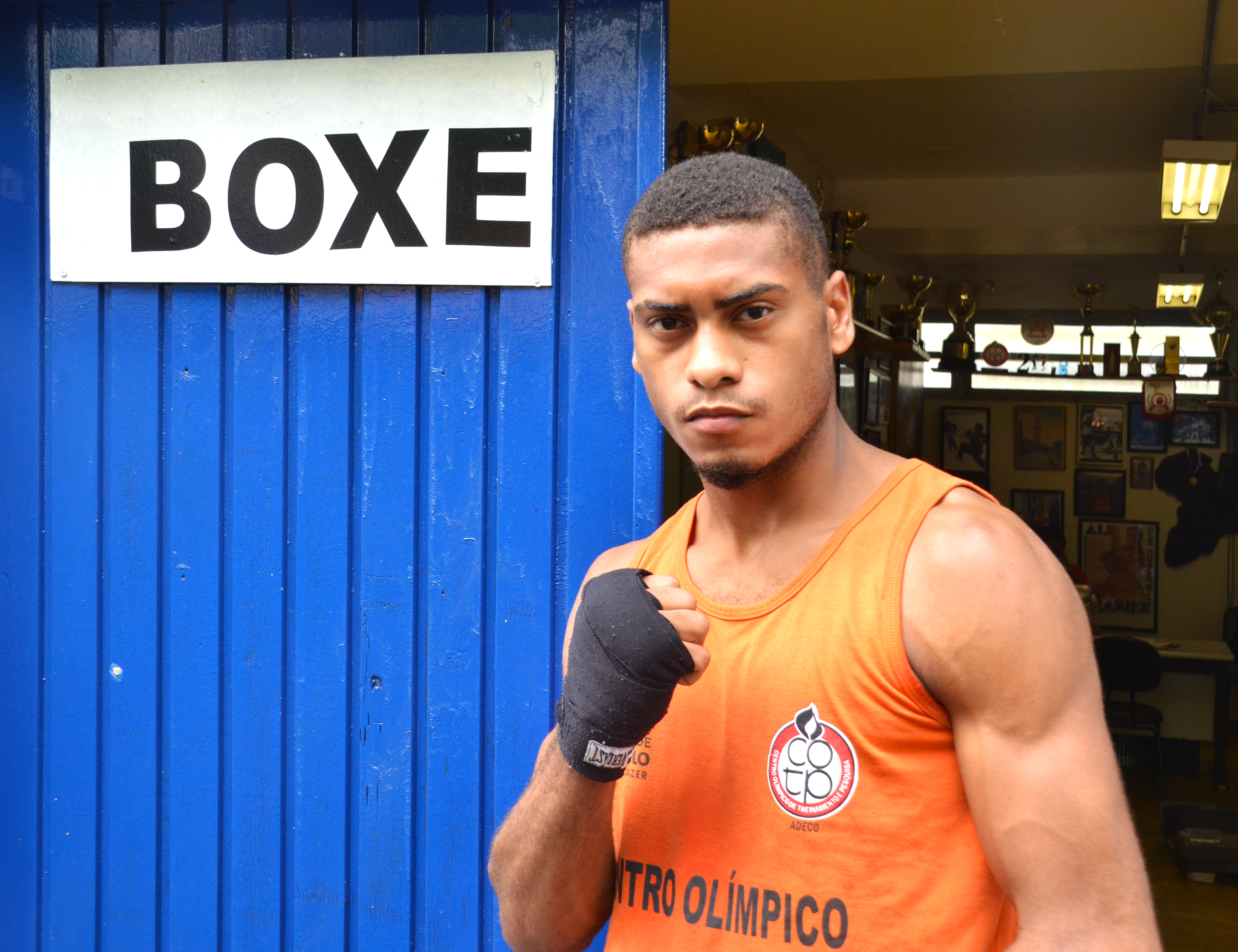 O atleta de boxe Luiz Carlos com uma cara séria, novamente com uma pose de guarda alta para a foto.