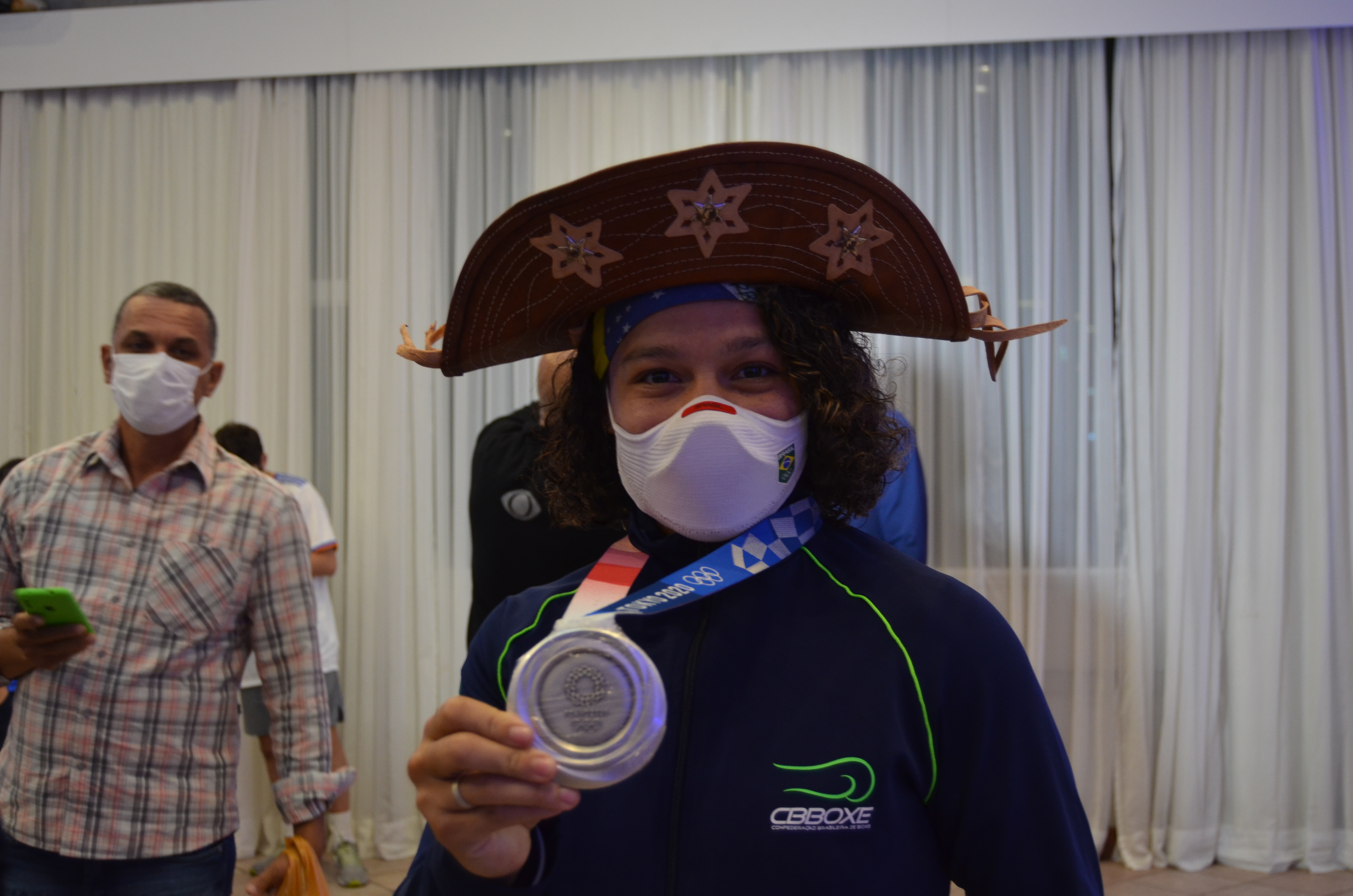 Na imagem, Beatriz Ferreira, com a medalha de prata na mão e o chápeu de cangaçeiro.