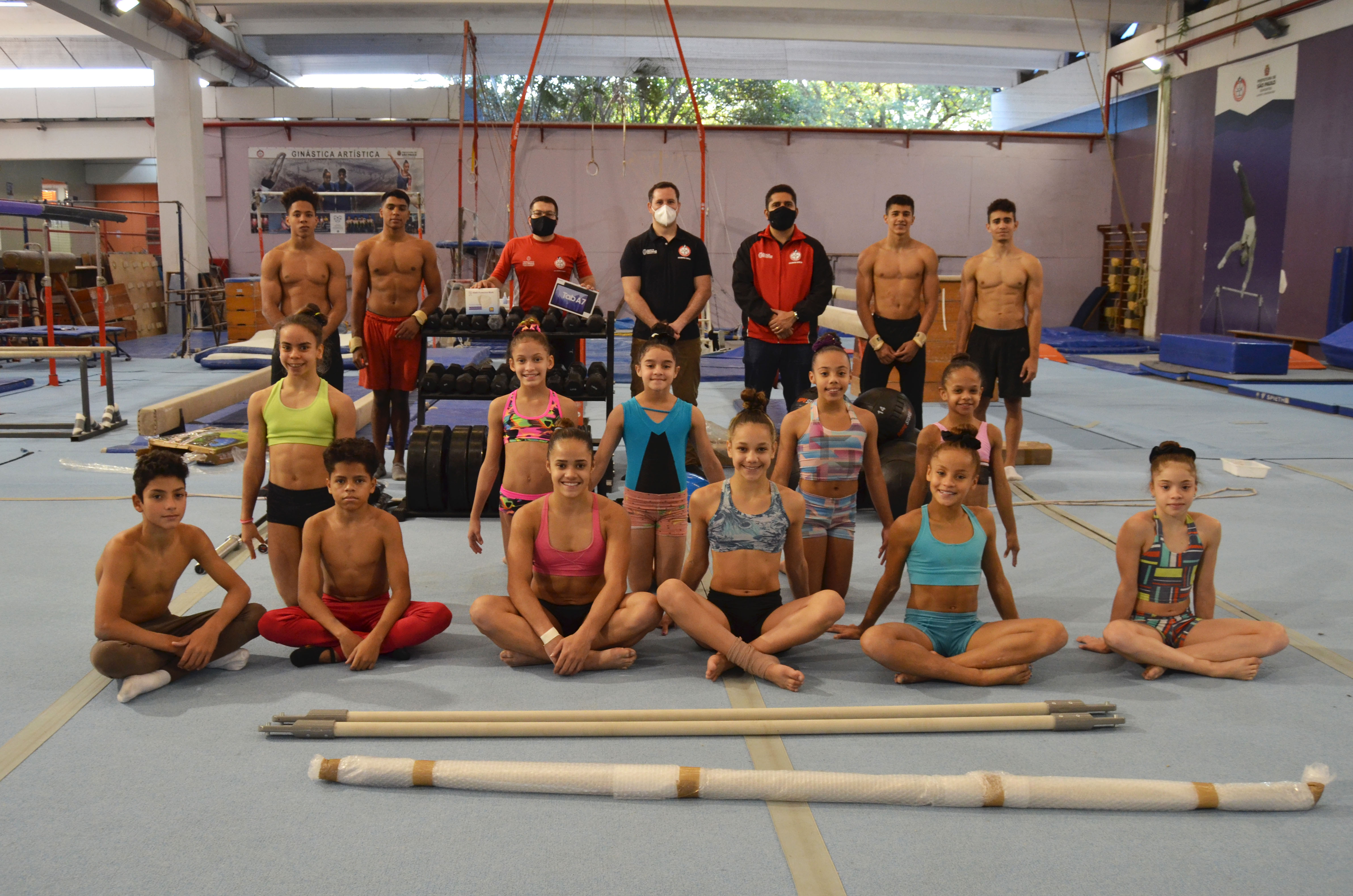 Alunos de Ginástica Artística do Centro Olímpico e gestores da SEME posam para foto com novos equipamentos adquiridos para a modalidade. Todos usam máscaras.