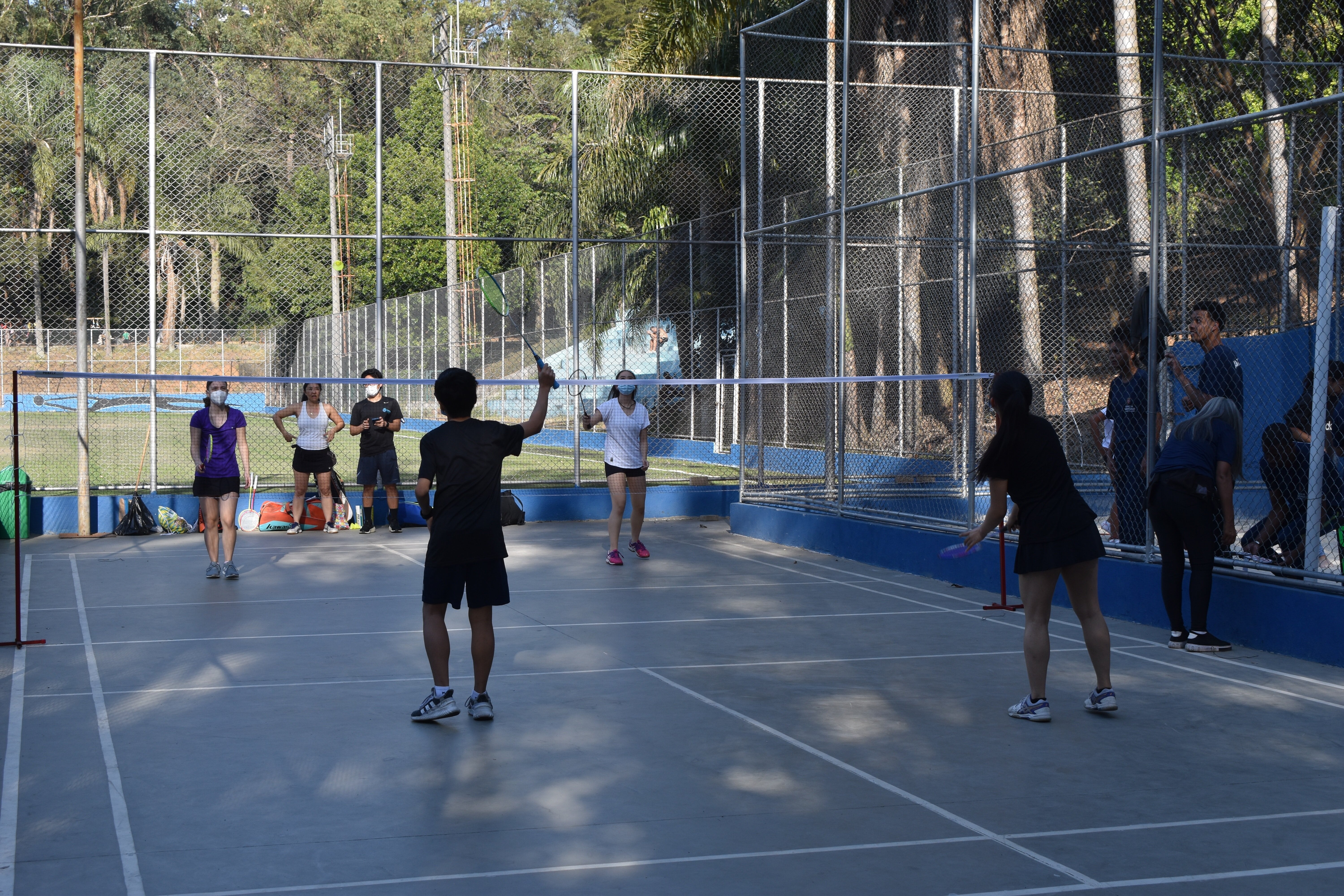 Na imagem, pessoas jogando badminton 