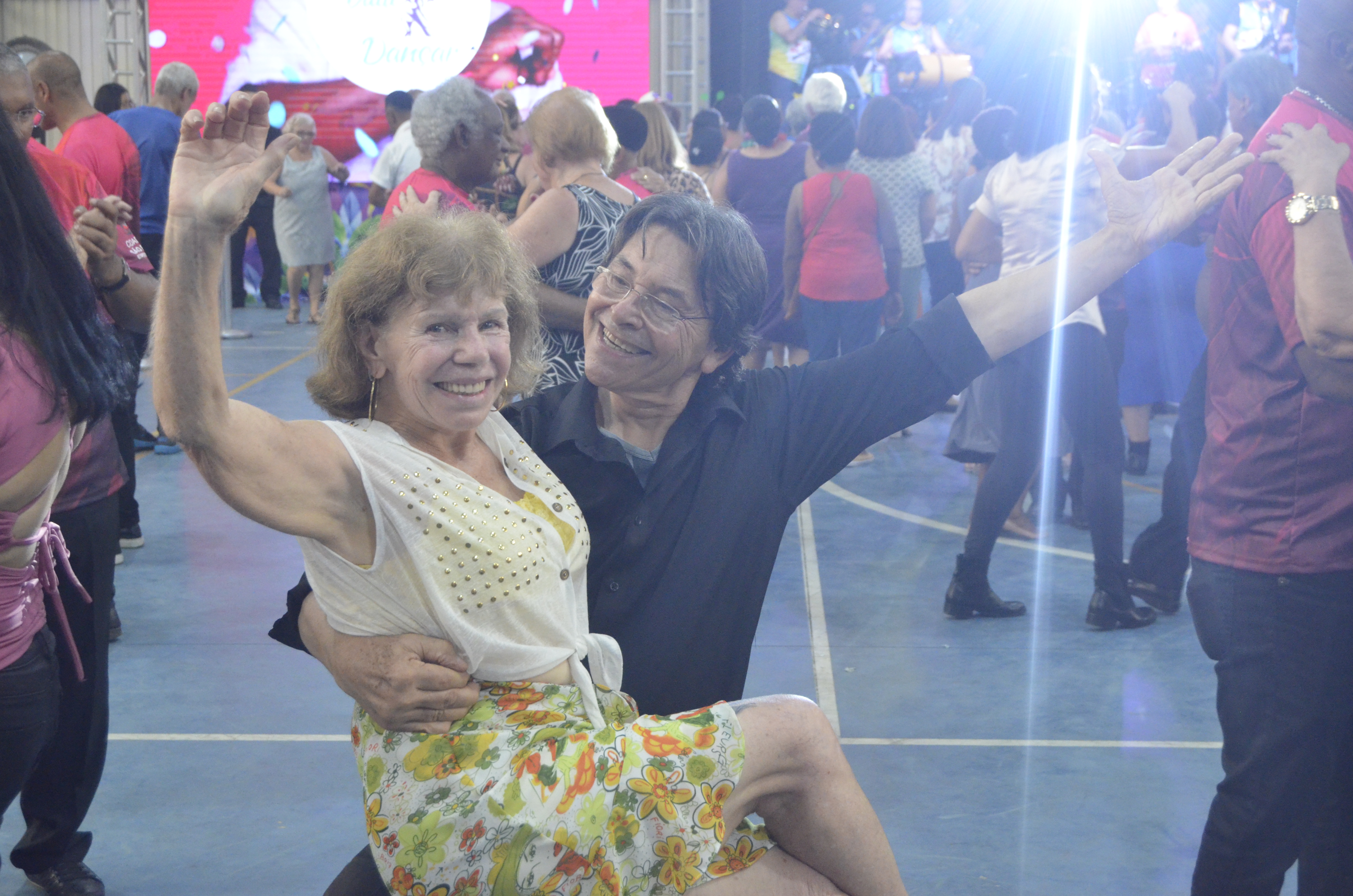 Na imagem, casal sorridente dançando no Vem Dançar.