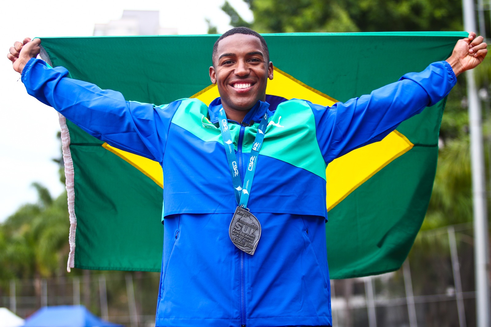 Na imagem é possível observar o atleta Erik Cardoso com a bandeira do Brasil.