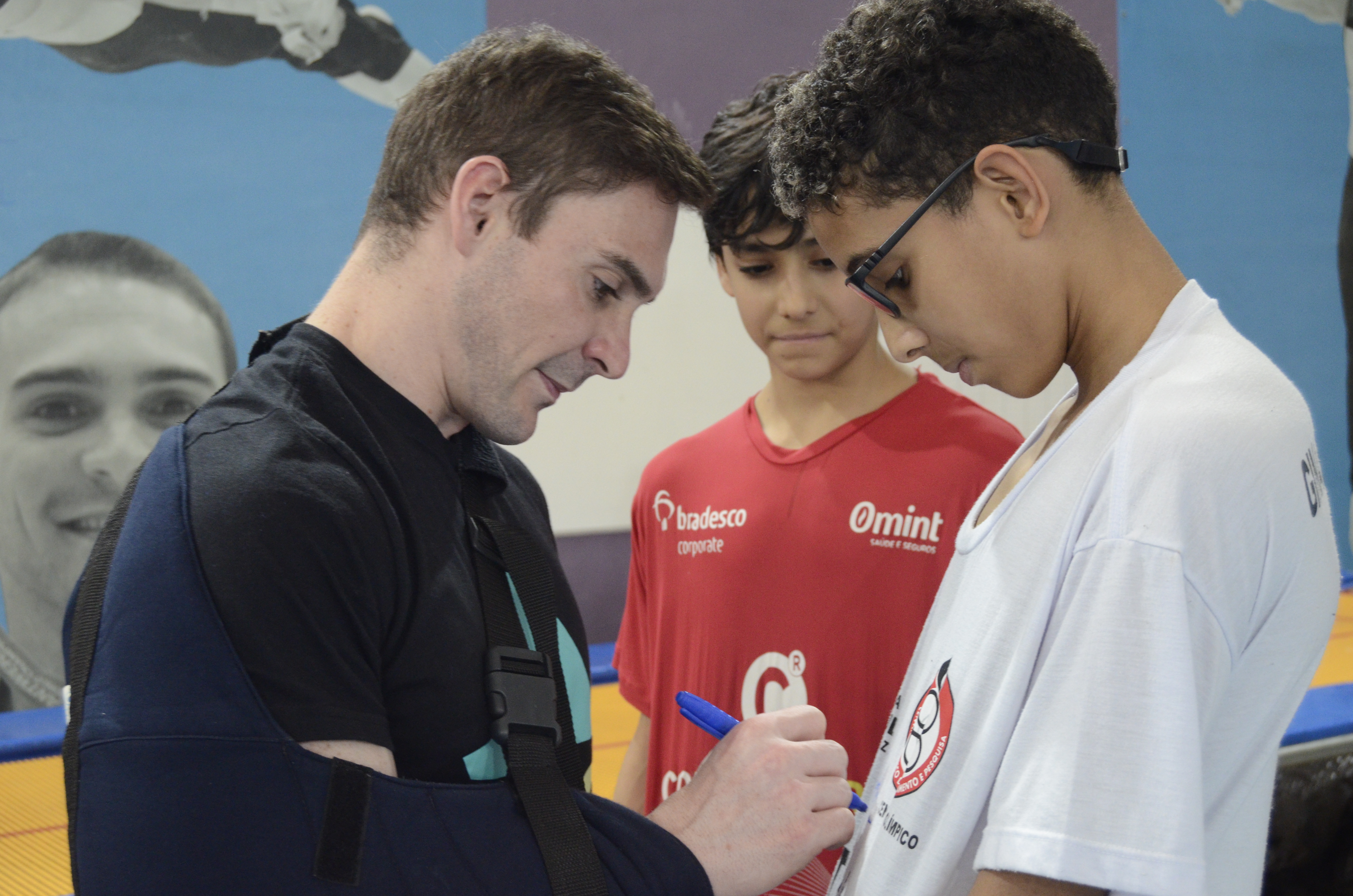 Na imagem, Arthur Zanetti autografando camiseta de atleta infantil de Ginástica Artistica.