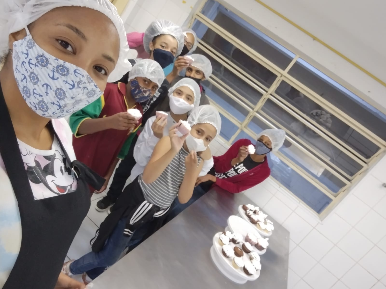 Foto tirada pela classe com todos segurando os bolinhos logo após a conclusão completa dos mesmos, todos utilizando máscaras.