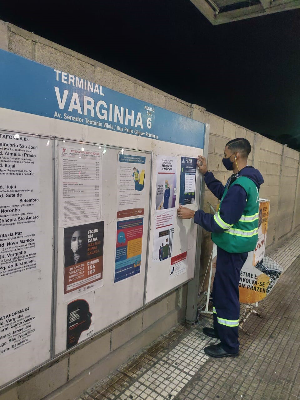 funcionário da prefeitura colando cartaz no terminal Varginha