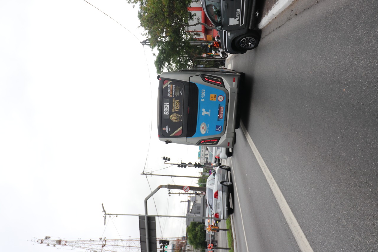 Imagem de um ônibus próximo SPTrans em movimento em uma avenida, com adesivo da Expo Internacional da Consciência Negra no vidro do Fundo deste ônibus