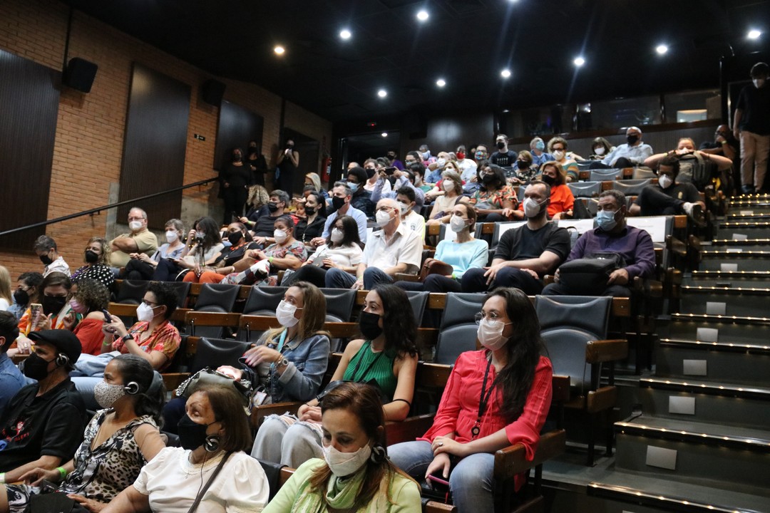 auditório lotado com mais de 50 pessoas reunidas.